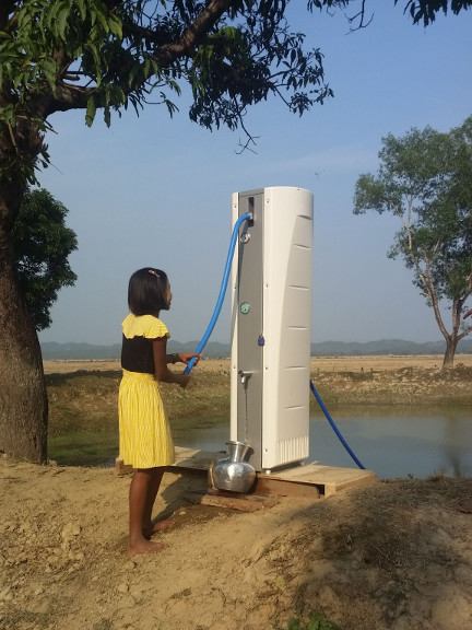 A girl operating a hand-powered Villagepump 500 next to a river