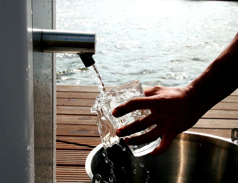 A glass being filled with clear water from the stainless steel tap of a Villagepump