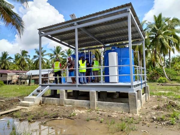 Raised platform with blue rainwater tanks and a Villagepump in Malaysia